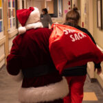 Santa walking down the hospital hallway to go visit children