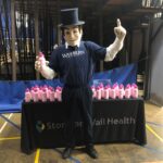 Washburn University Ichabod posing with the pink water bottles that have Stormont Vail Health logo on them.
